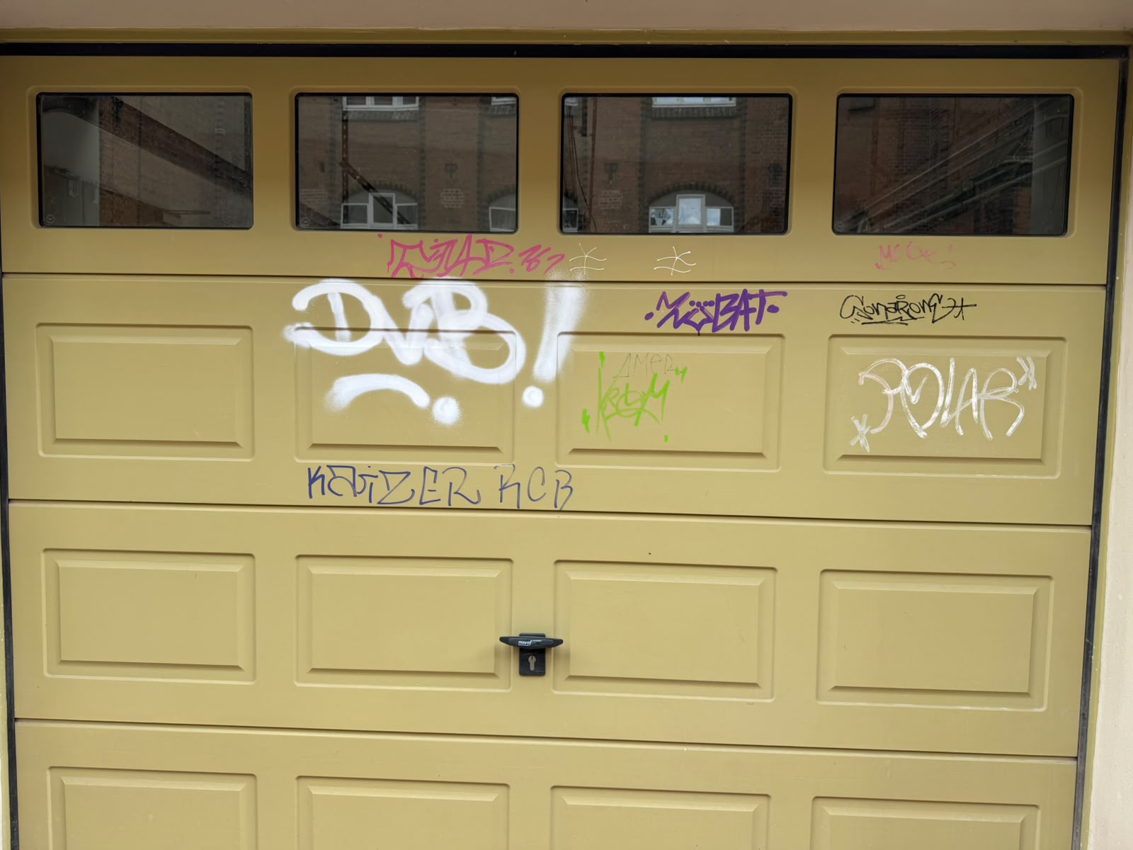 Vorher: Graffiti auf einer lackierten Holzoberfläche an einem Garagentor
